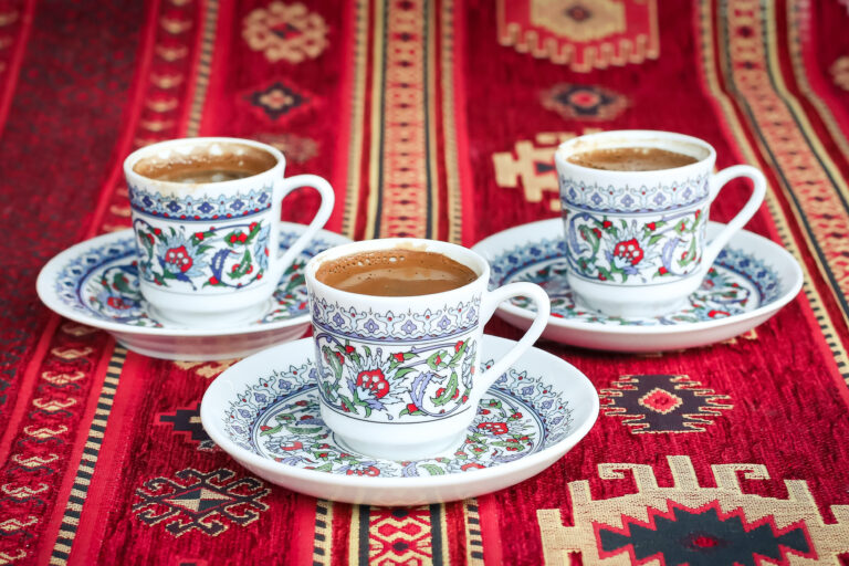 Three tea cups filled with tea placed in a triangle position on a textile pattern.